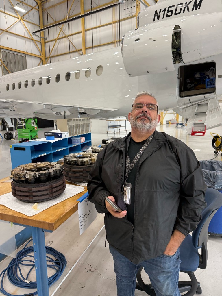 Technician beside a business jet with wheel assemblies on the work table
