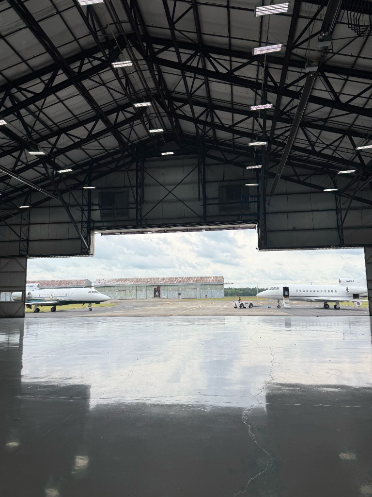Hangar doors open to two business jets parked on the ramp