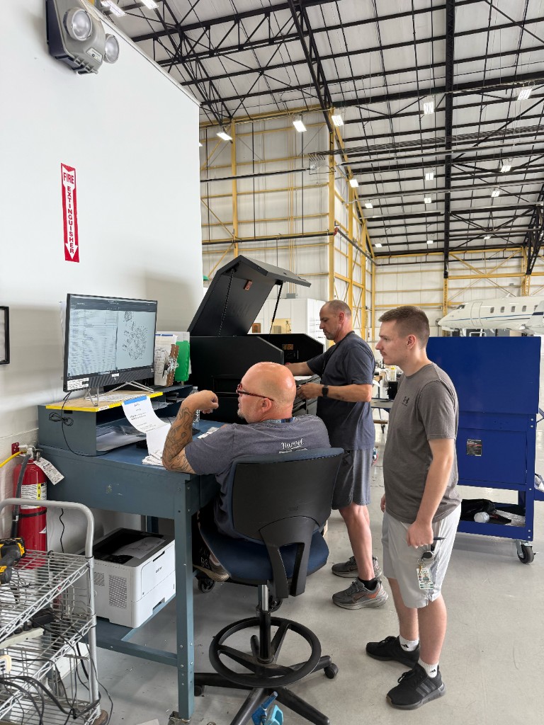 Shop computer station with an aircraft in the hangar beyond